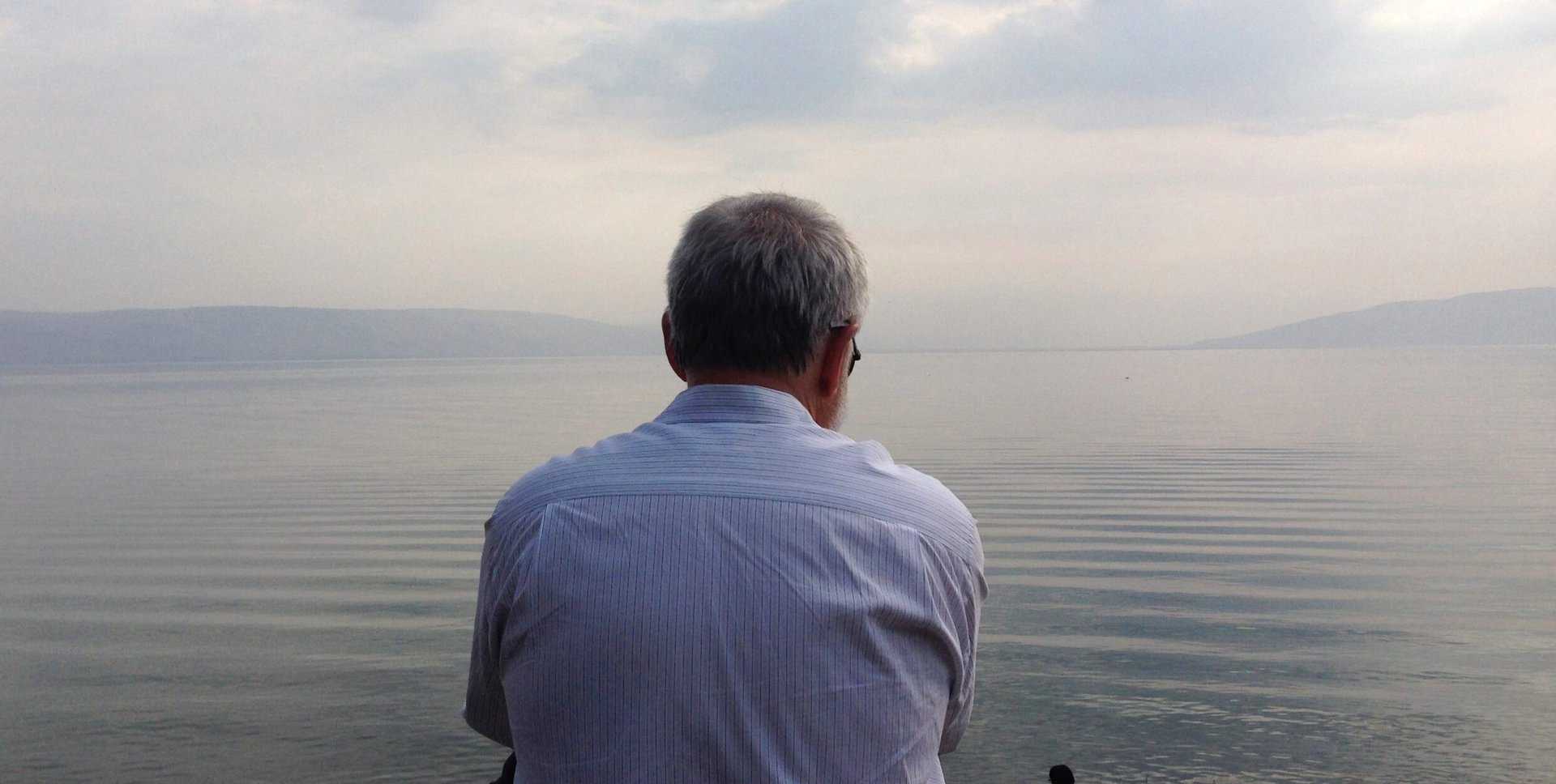 Swami Premodaya sitting at the Sea of Galilee
